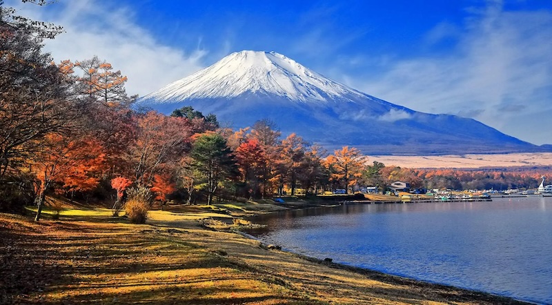 Travelers walking along Lake Yamanakako shoreline with Mount Fuji in the background